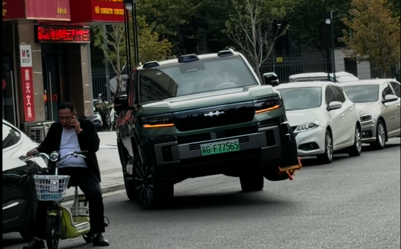 BYD FCB Bao 8 едет на трёх колёсах с прикреплённым блокиратором колеса по общественной улице.